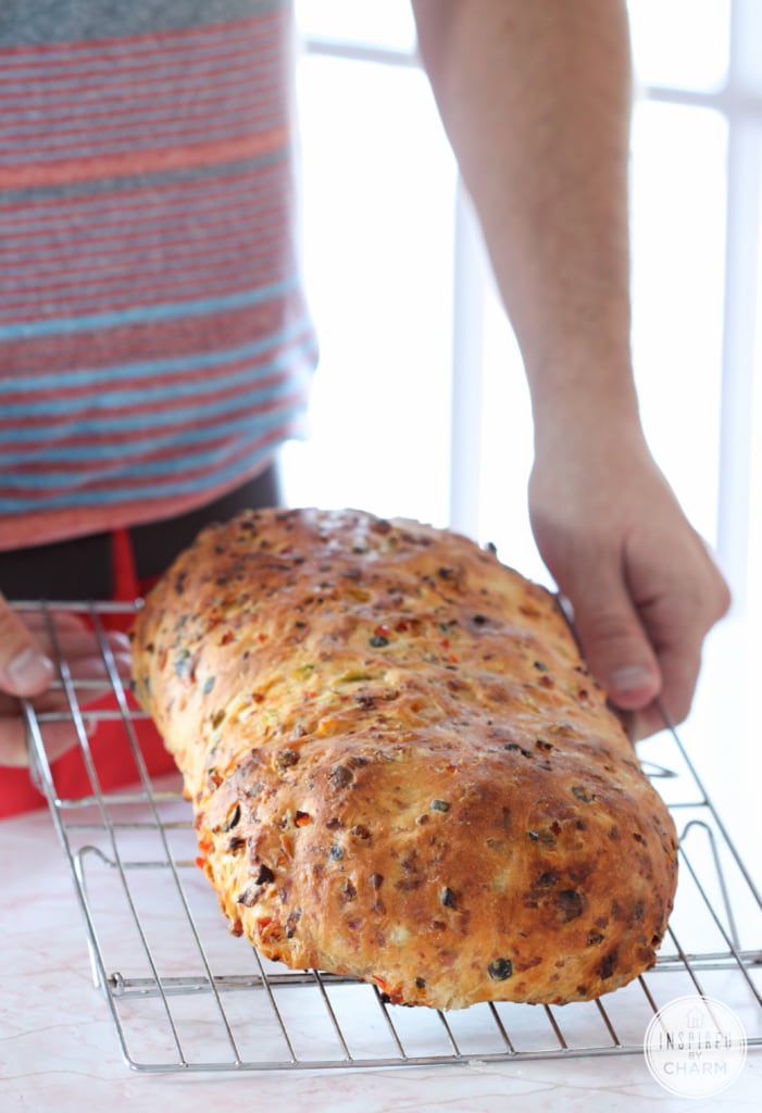 man holding a cooling rack with a loaf of bread on top 