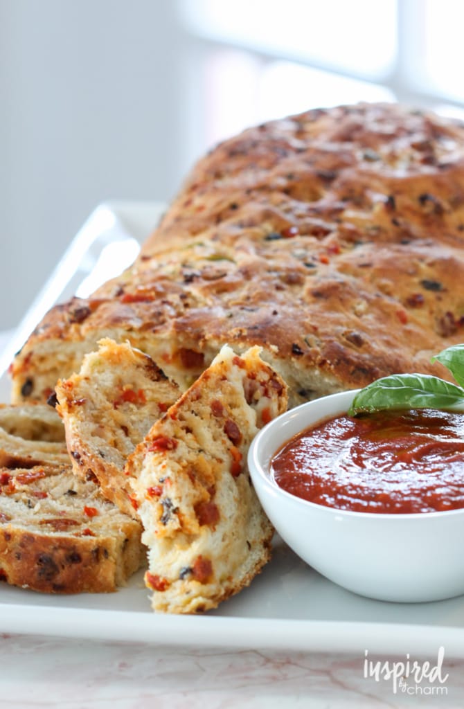 close up of pizza bread with a cup of marinara sauce