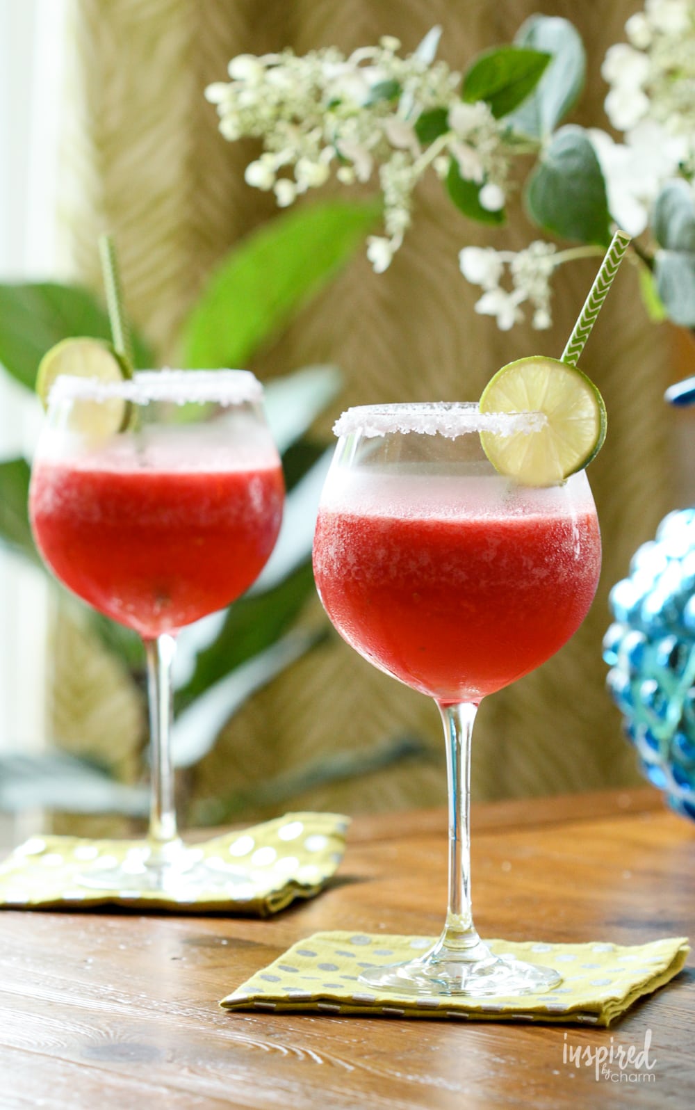 two watermelon margaritas in glasses with lime garnish and paper straw.
