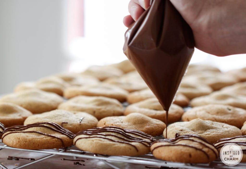 hand drizzling chocolate onto stuffed peanut butter cookies.