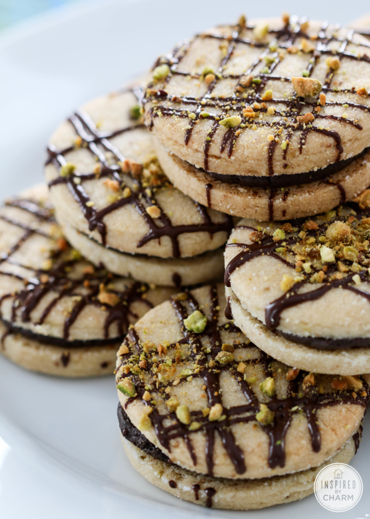 Pistachio Shortbread Cookies with Dark Chocolate Filling on a cake stand.