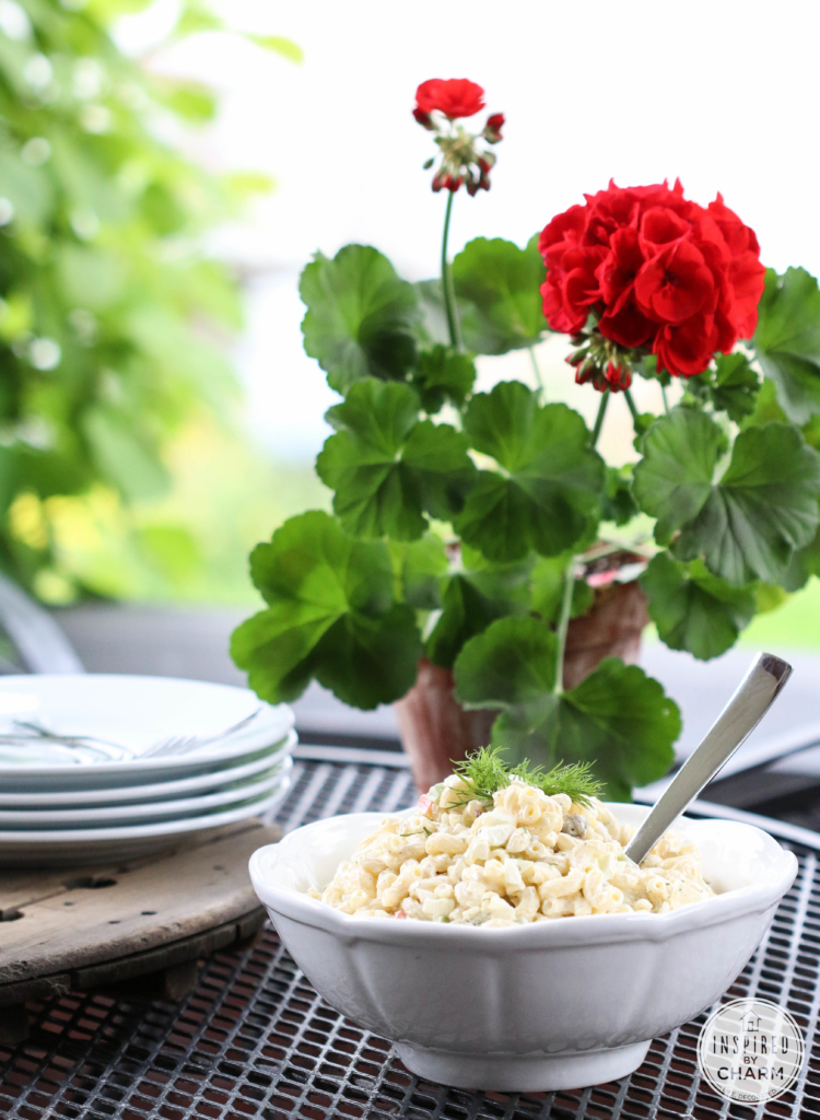 macaroni salad side dish on a table with fresh flowers in a pot