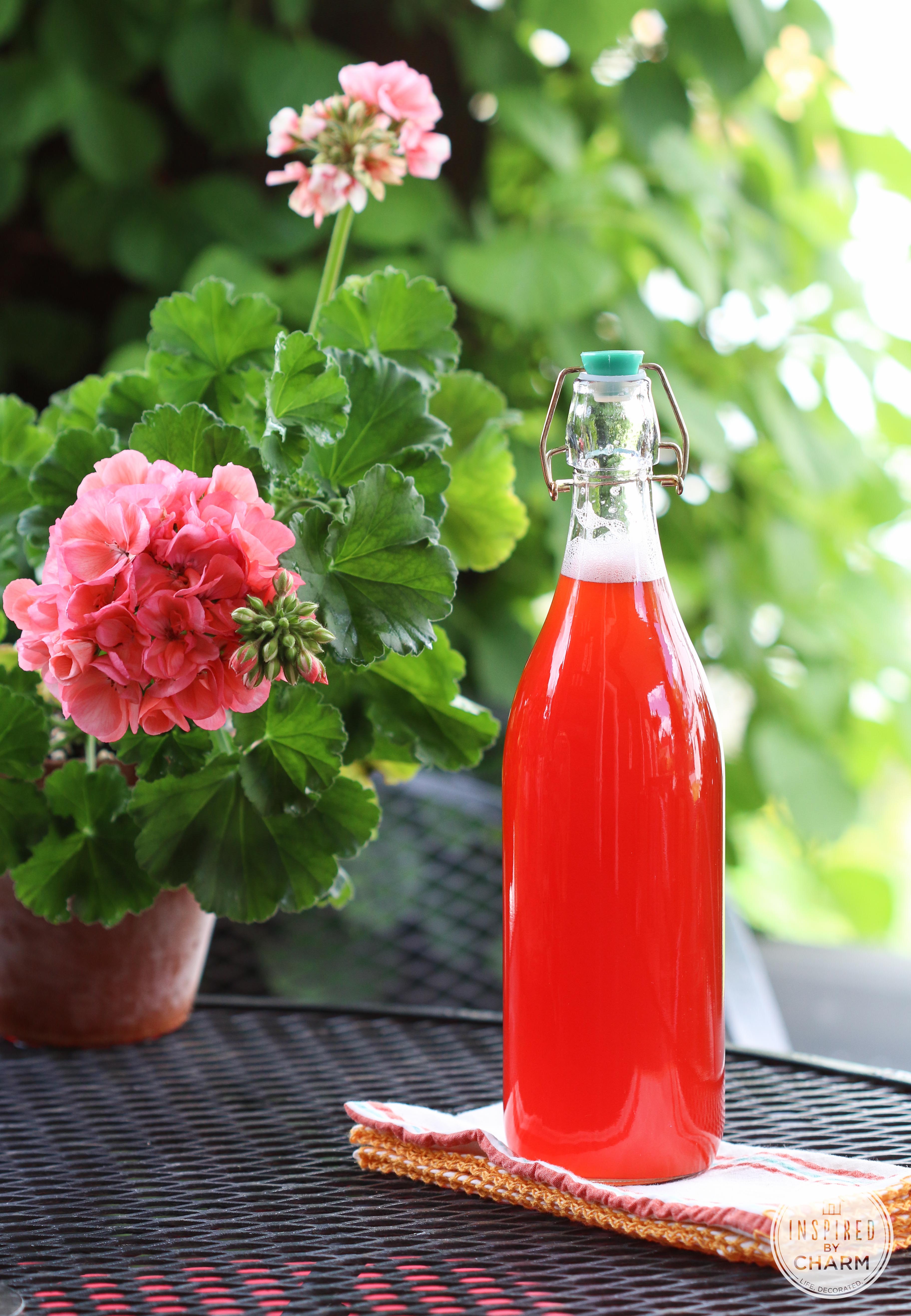 Homemade Strawberry Rhubarb Syrup in a bottle on a table.
