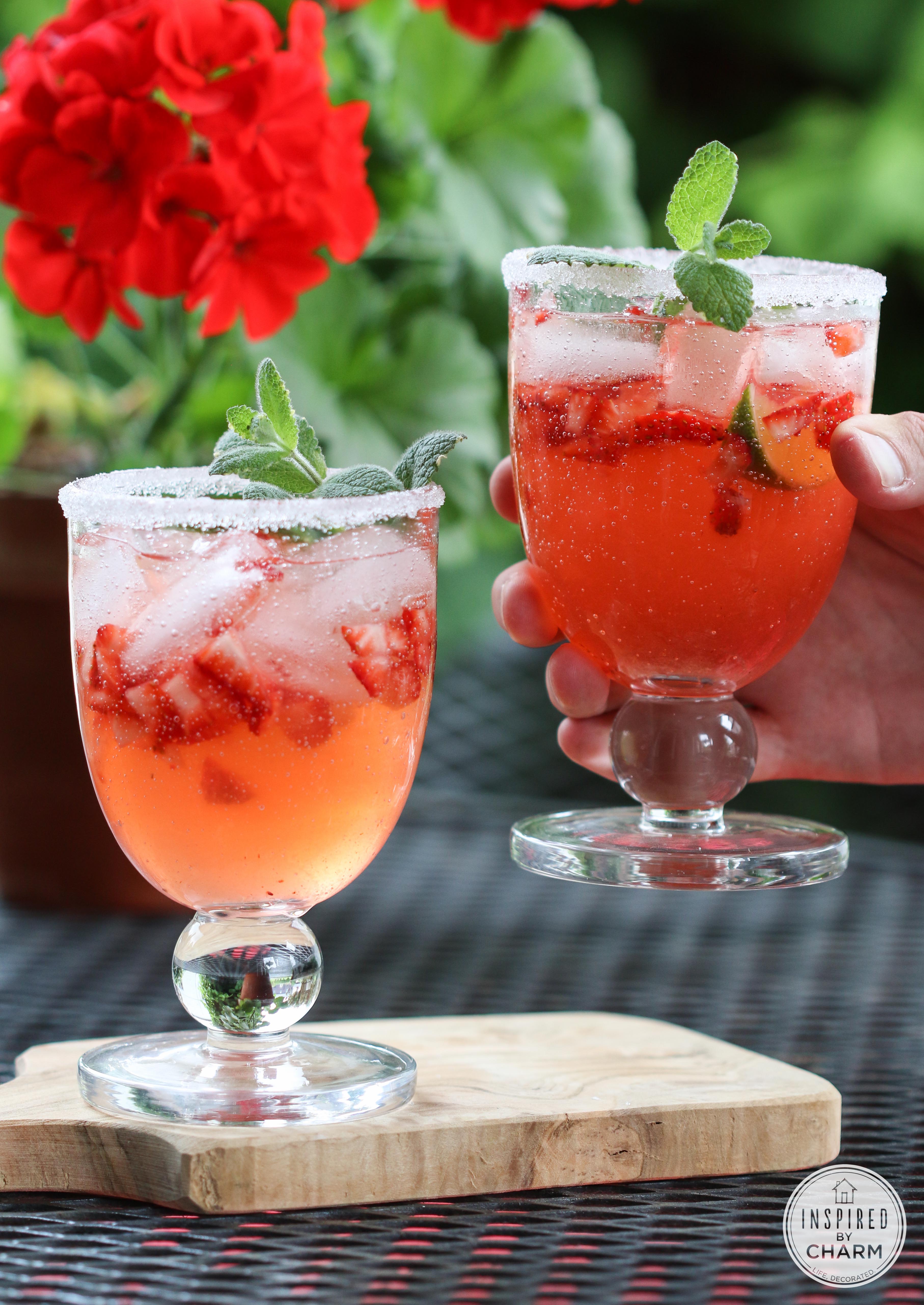 Refreshing Strawberry Rhubarb Margaritas on a cutting board with a hand holding one.