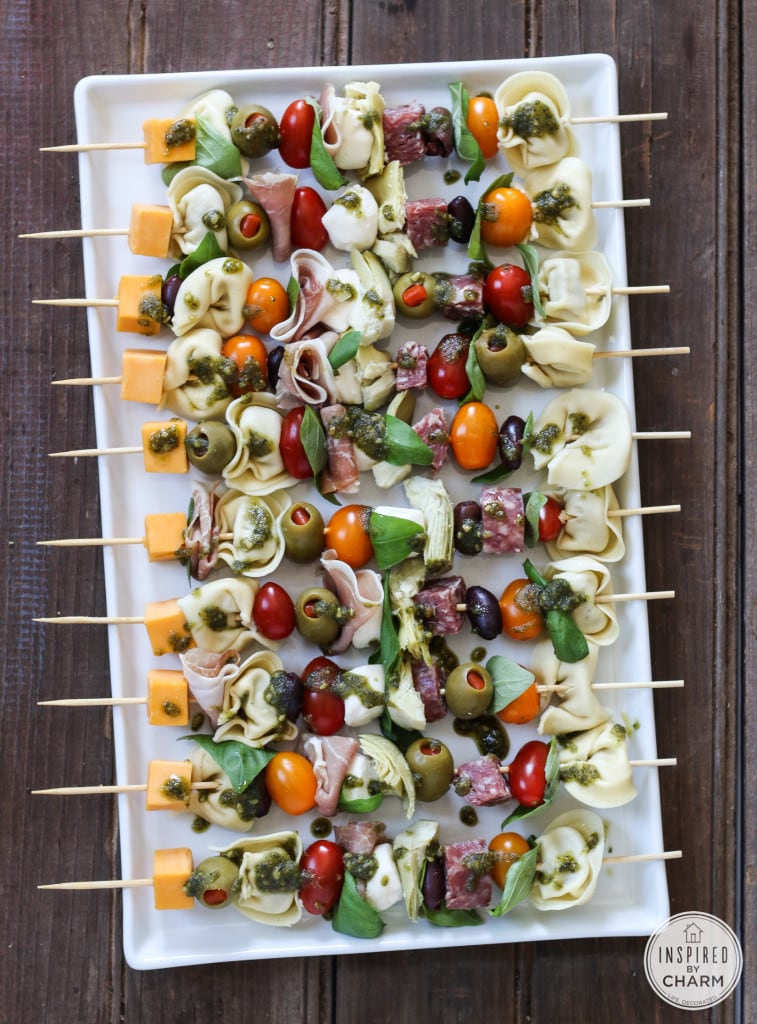 Antipasto kabobs - skewer filled with cheese, meat, olives, tomatoes, and fresh basil drizzled with a pesto sauce.