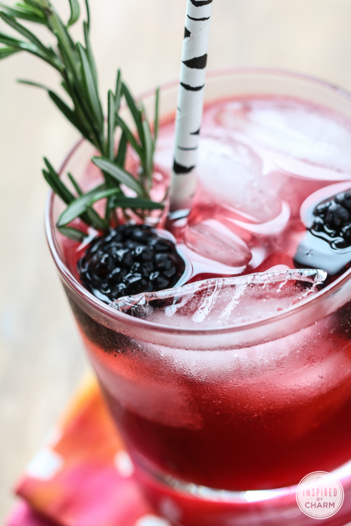 purple hued drink garnished with blackberries and rosemary