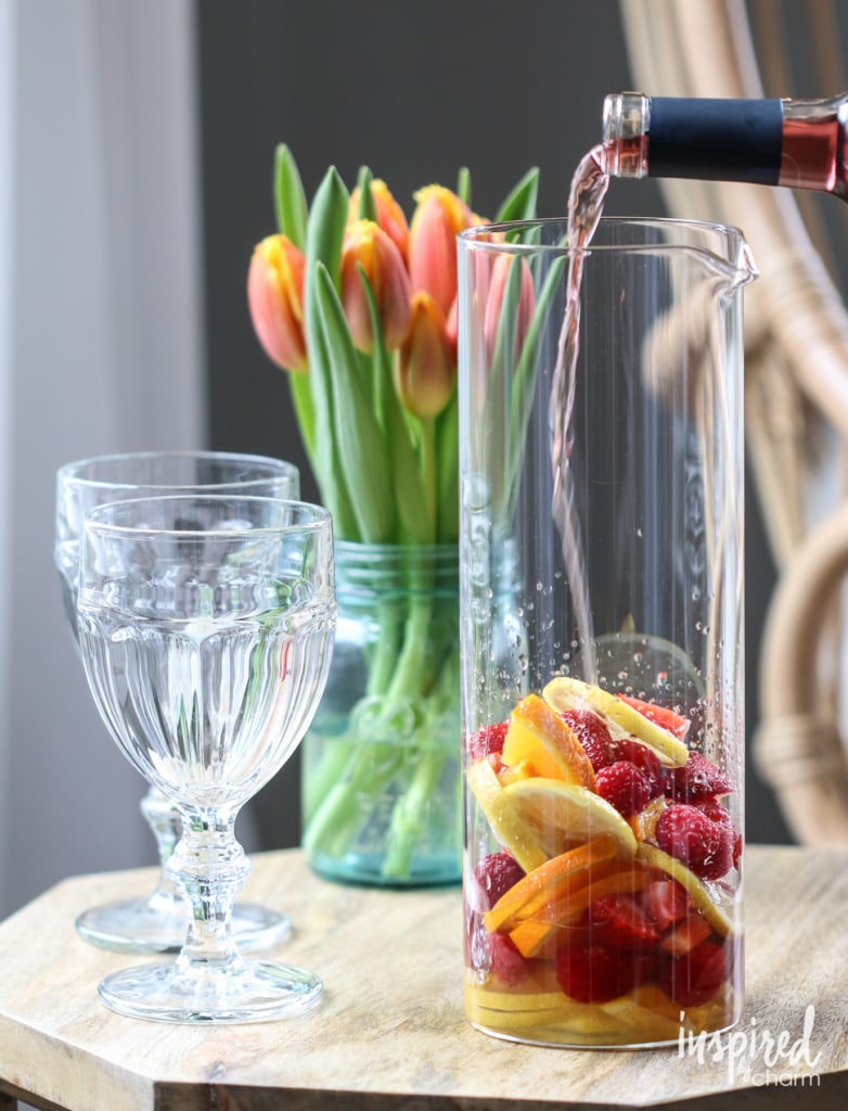 pouring wine into a pitcher of fruit. 
