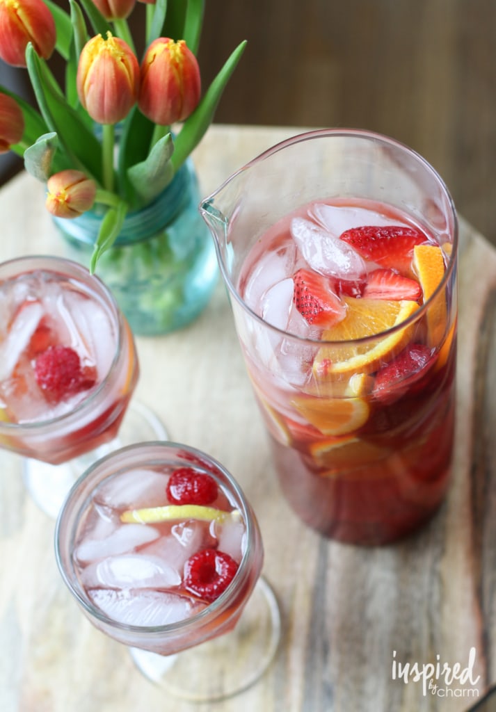 a pitcher and two glasses of rosé sangria with fruit. 