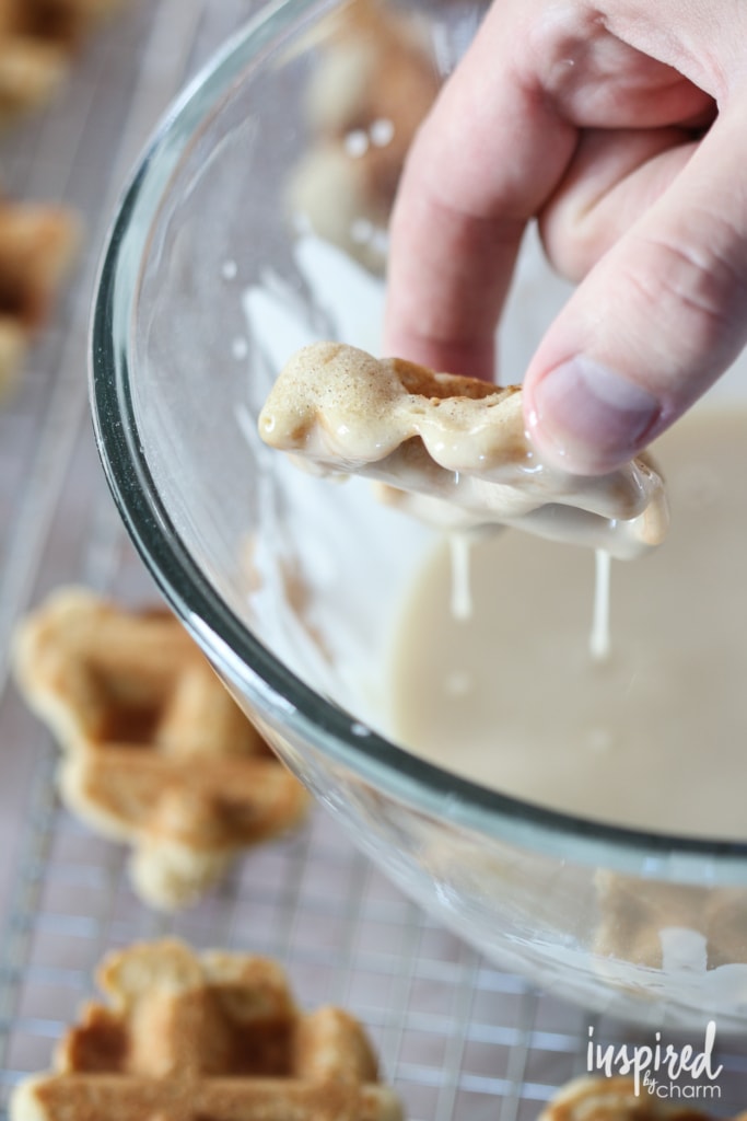hand dipping waffle cookies into maple glaze.
