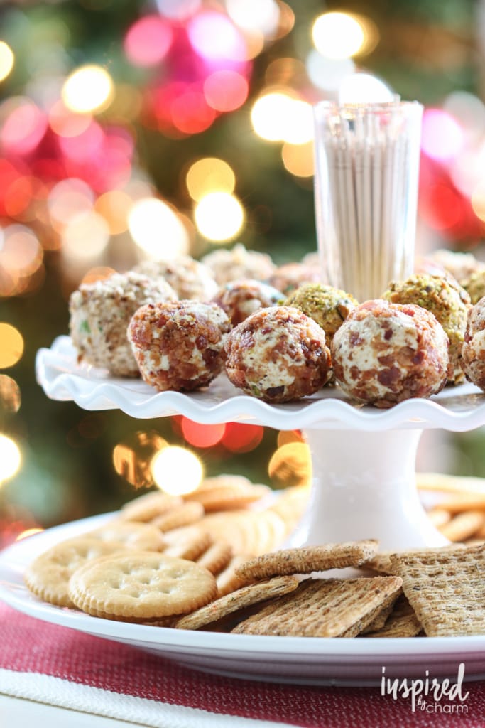 mini cheeseballs on a cake stand with a plate of crackers underneath