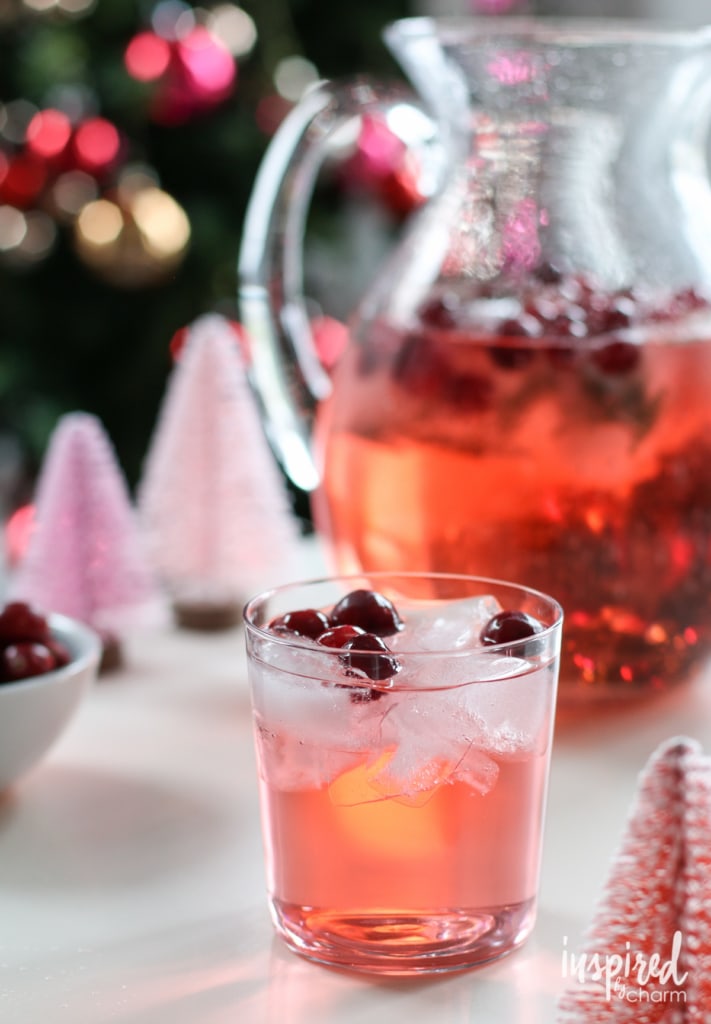Pitcher with cranberry holiday punch with a full glass in front of it