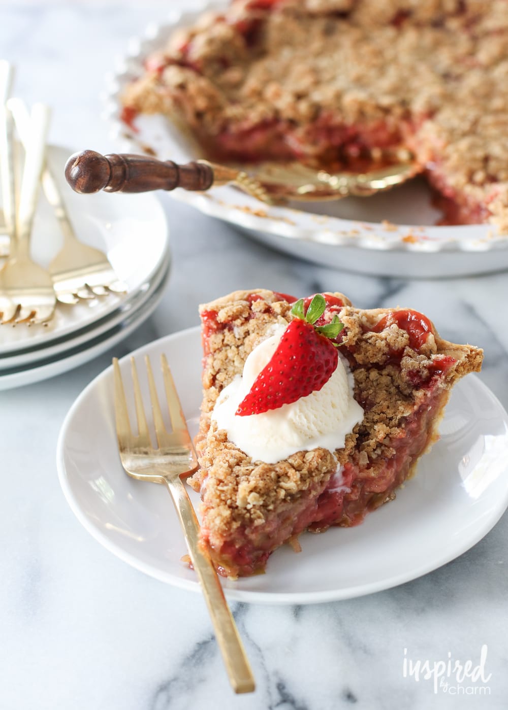 The BEST Strawberry Rhubarb Crumble Pie served on plate with a whole pie in the background.