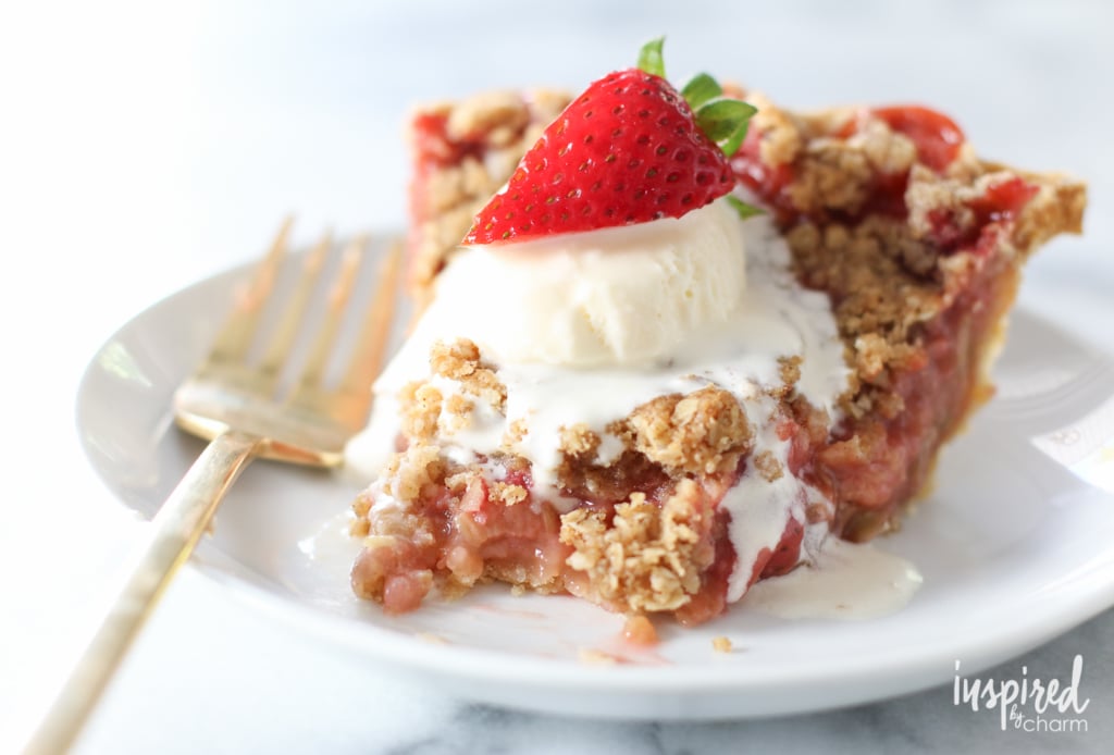slice of  strawberry rhubarb crumble pie on a plate with ice cream.