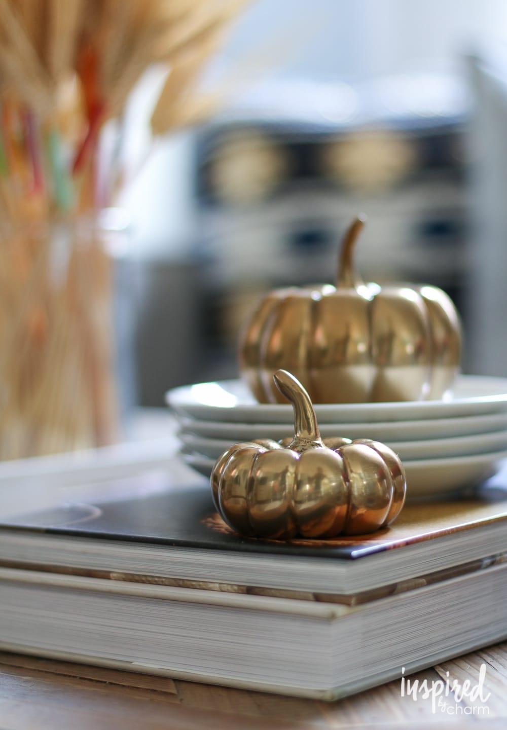 brass pumpkins on a book and stack of plates.