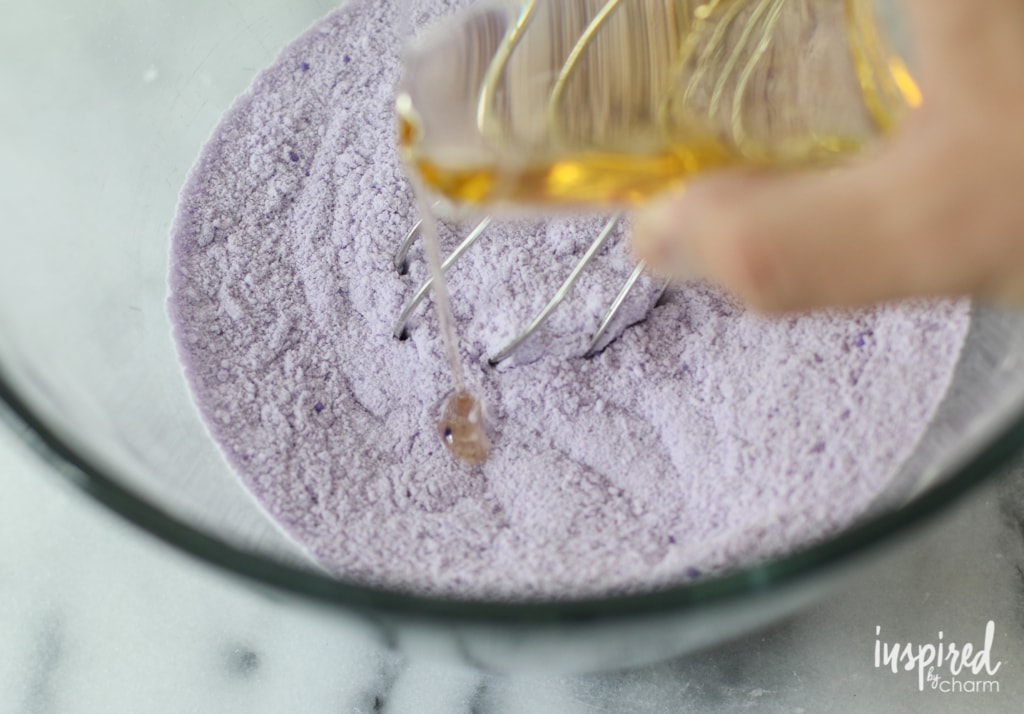 pouring wet ingredients into dry DIY bath bomb mixture