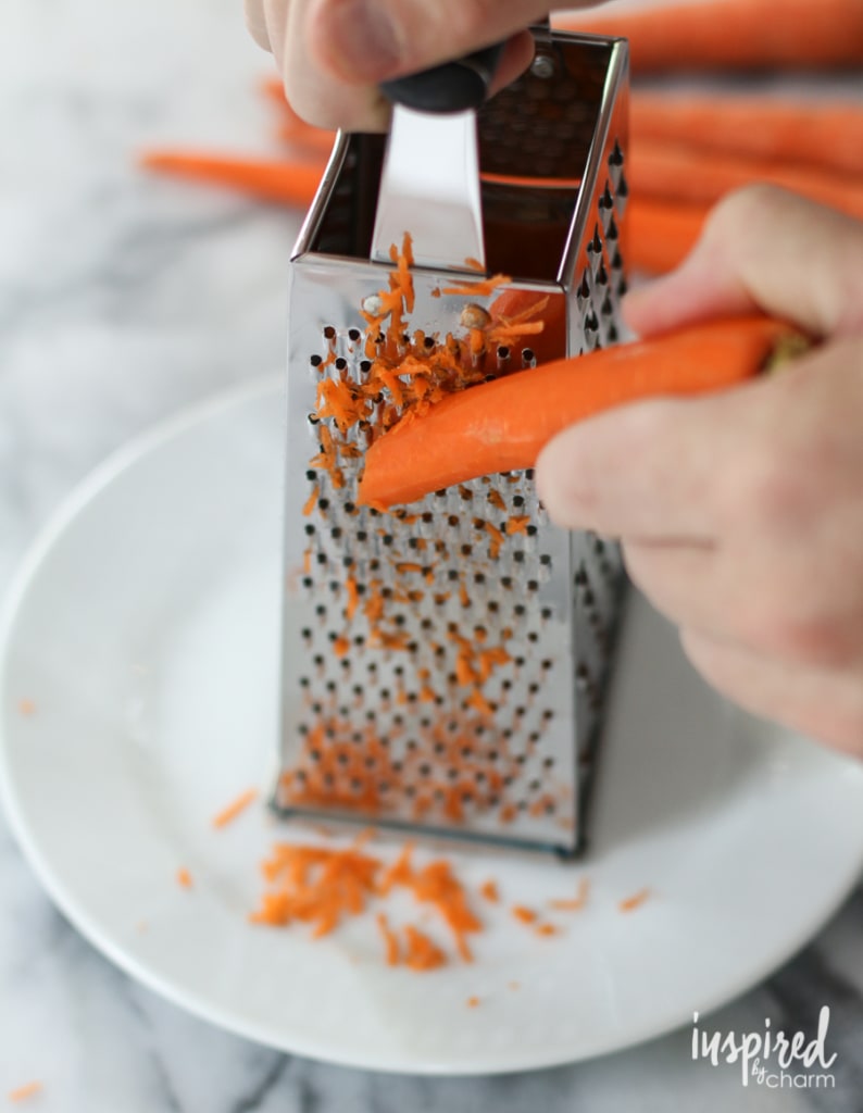 hand grating carrot on box grater.