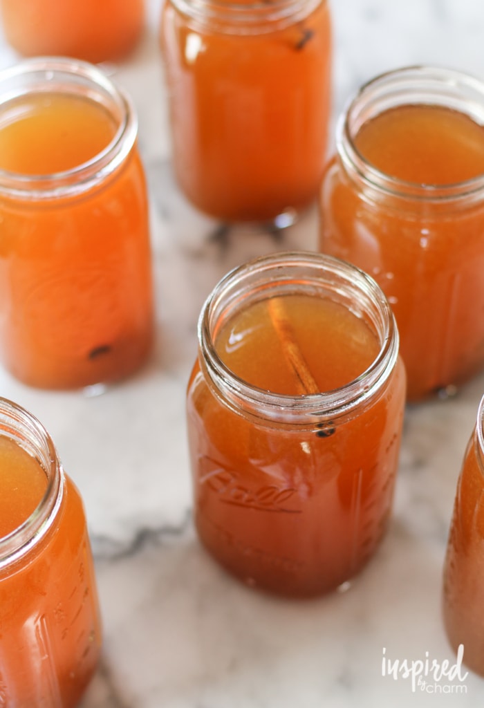Mason jars filled with homemade moonshine with apple flavor and cinnamon sticks