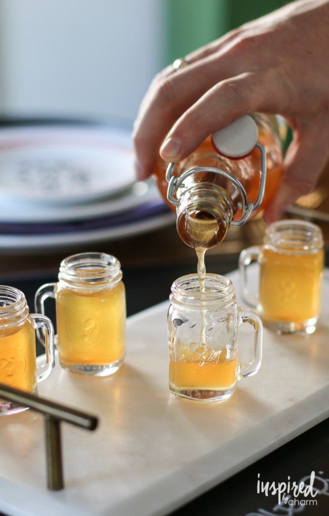 Pouring homemade moonshine into tiny mason jar shot glasses