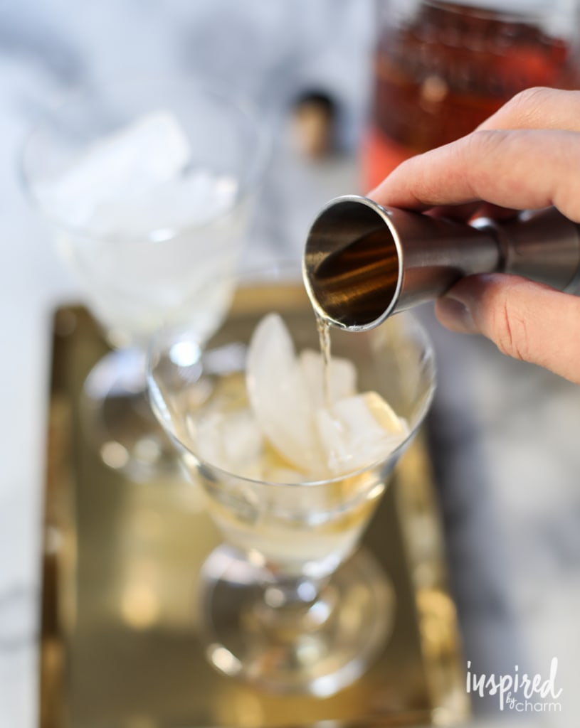 pouring bourbon into a glass filled with ice