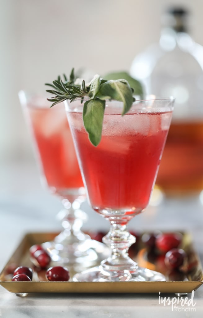 Cranberry Bourbon Cocktail in glass with fresh herb garnish.