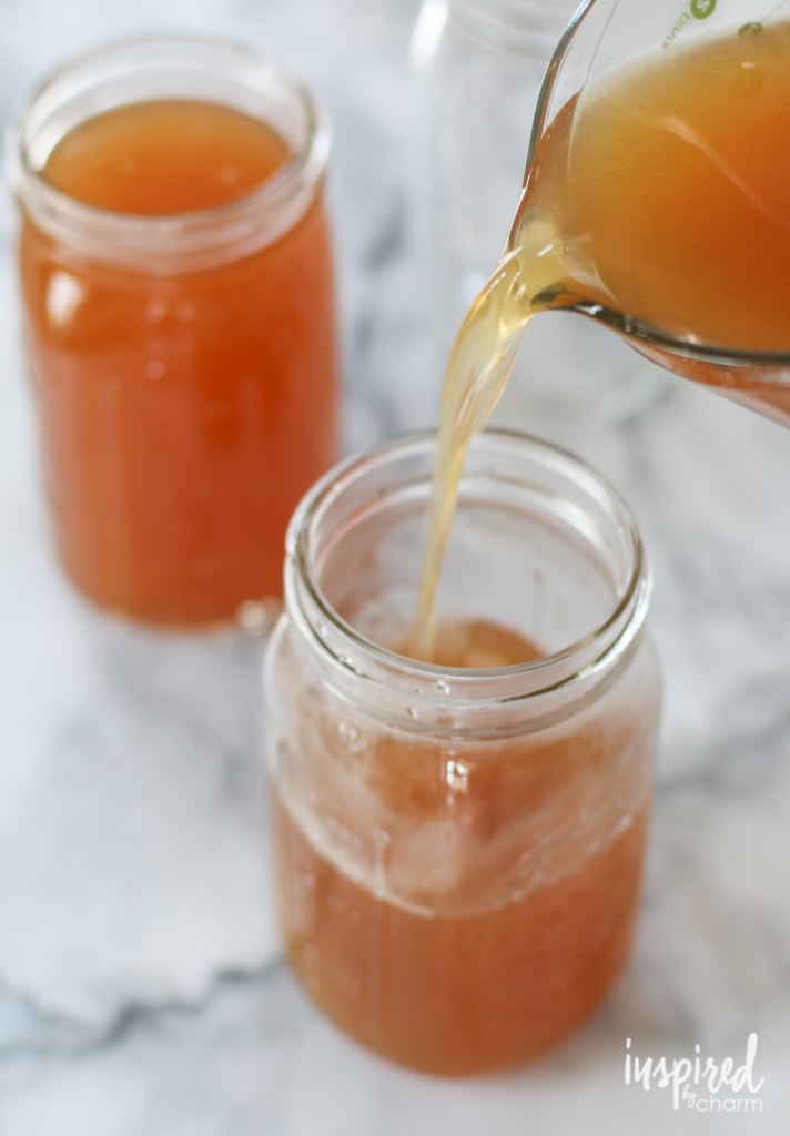 Pouring DIY apple moonshine into mason jars for storage.