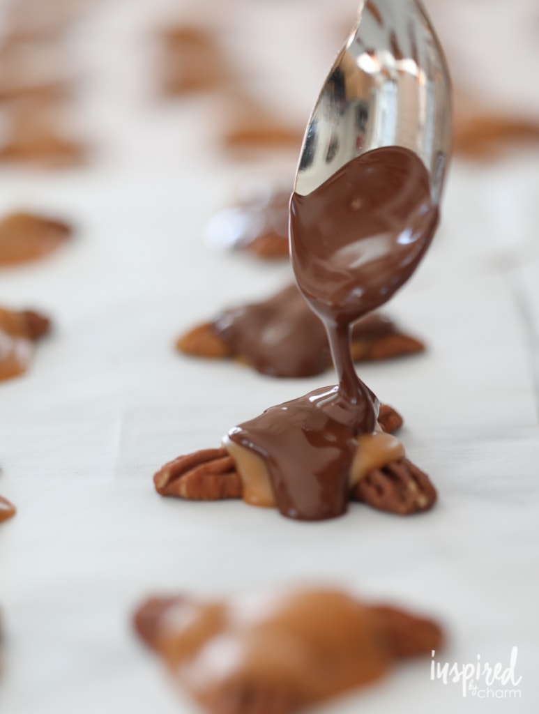 a spoon of melted chocolate over pecans and caramel for turtle candy