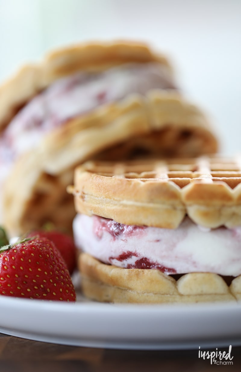 Homemade Peanut Butter Waffle and Jelly Ice Cream Sandwiches on a plate with a strawberry.