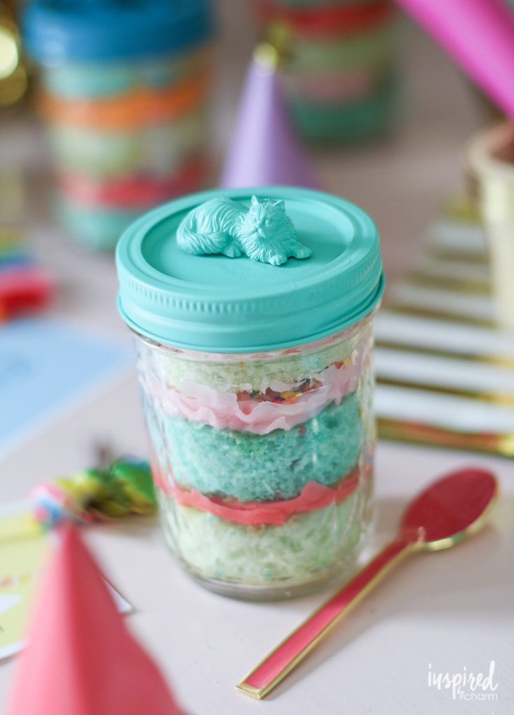 colorful cake in a jar with a spoon beside it