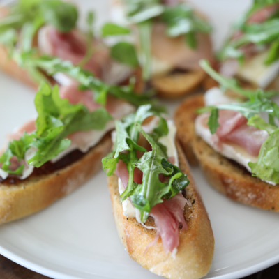 This Brie, Fig, and Prosciutto Crostini recipe makes a flavorful and easy appetizer. #appetizer #crostini #fig #arugula #brie #prosciutto