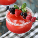 Raspberry Strawberry Margaritas in a glass with berries and mint garnish.