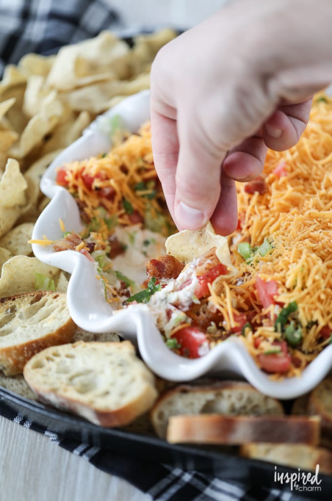 a hand scooping a chip into blt dip.