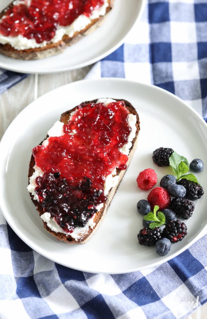 toast with ricotta and jam served on a plate with fresh berries.