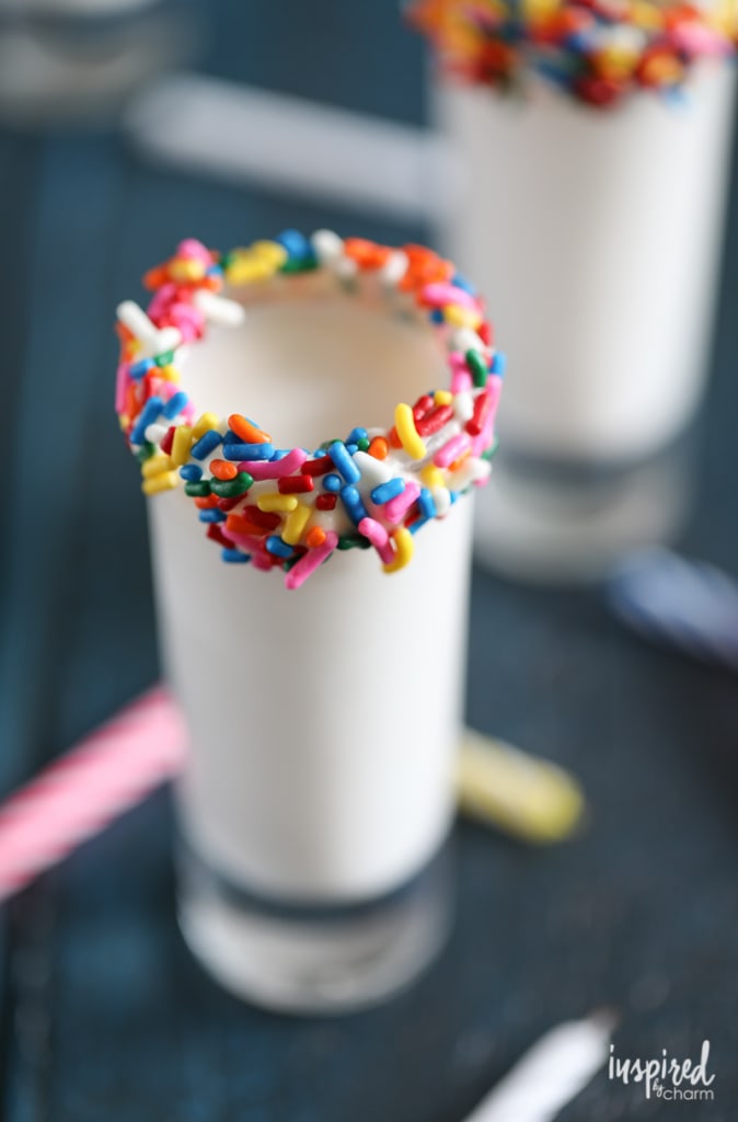 close up of shot glass rimmed with sprinkles filled with a birthday cake flavored shot. 