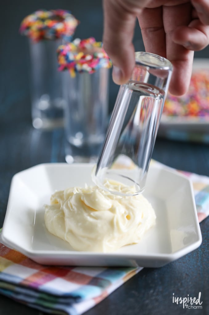 hand dipping a shot glass into frosting. 