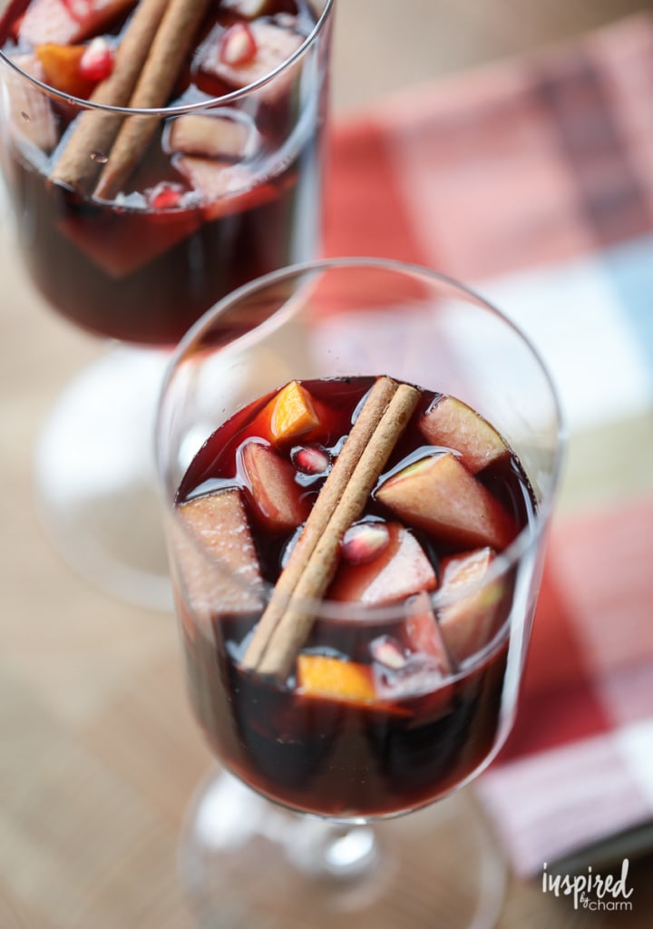 two glasses of red wine fall sangria with fruit and cinnamon sticks. 