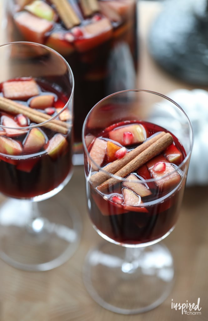 Autumn Harvest Fall Sangria Recipe in to wine glasses garnish with apples, cinnamon stick, and pomegranate seeds.