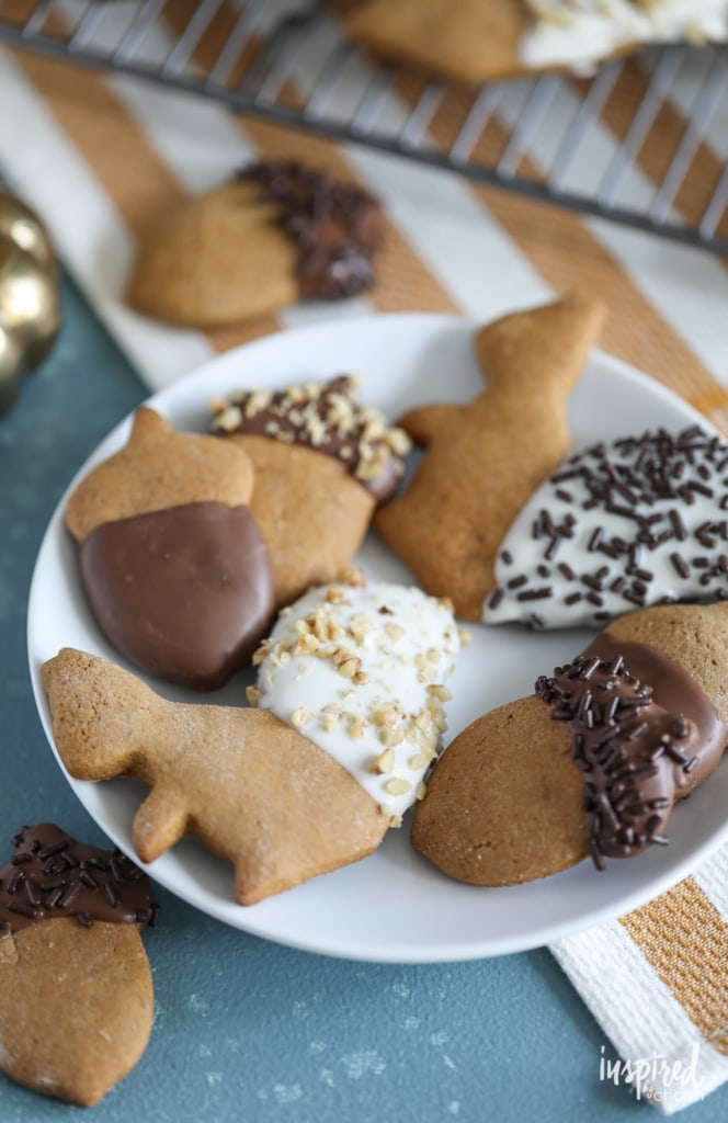 Chocolate Dipped Gingerbread Cookies shaped liked acorns and squirrels dipped in chocolate and stacked on a plate. 