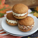 three Pumpkin Whoopie Pies with Salted Caramel Cream Cheese Frosting stated on a plate.