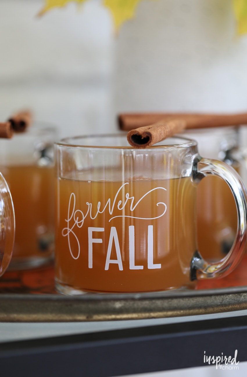 glass mug that says Forever Fall in vinyl lettering filled with hot cider