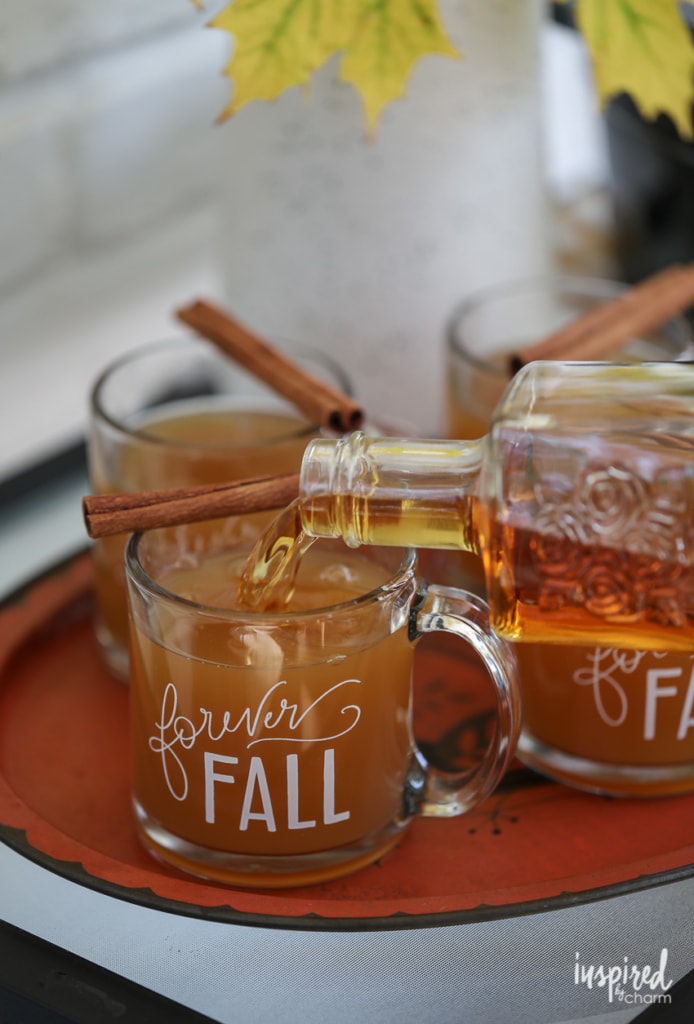 alcohol being poured into cup of mulled cider