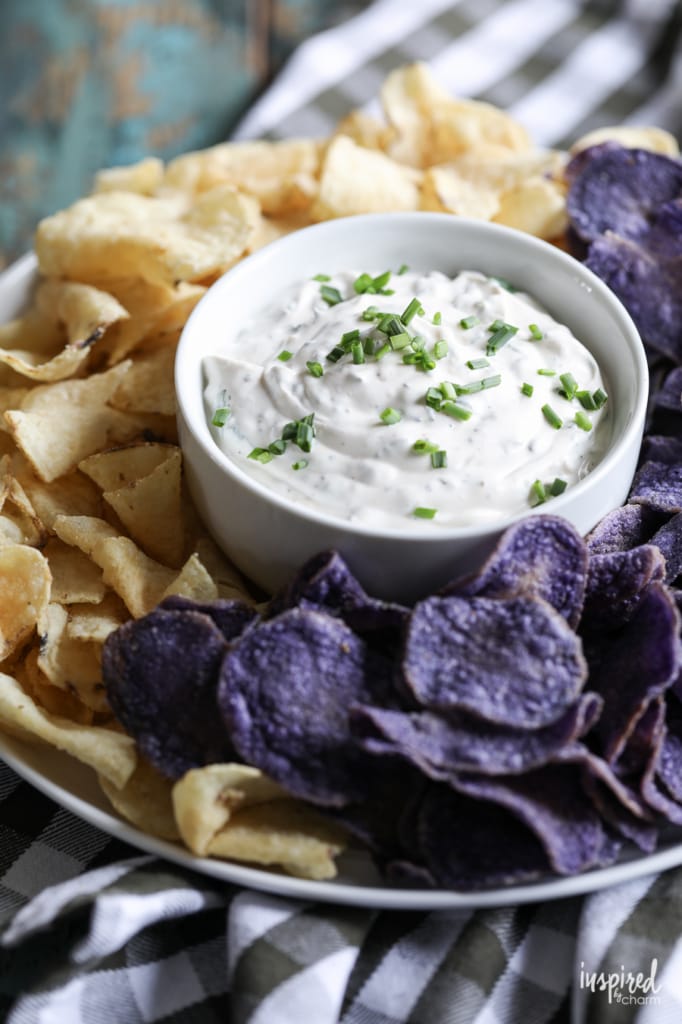 chips surrounding a bowl of dip made with herbs