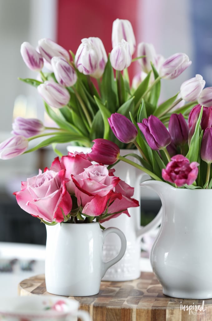 tulips and roses in vases on a dining table.