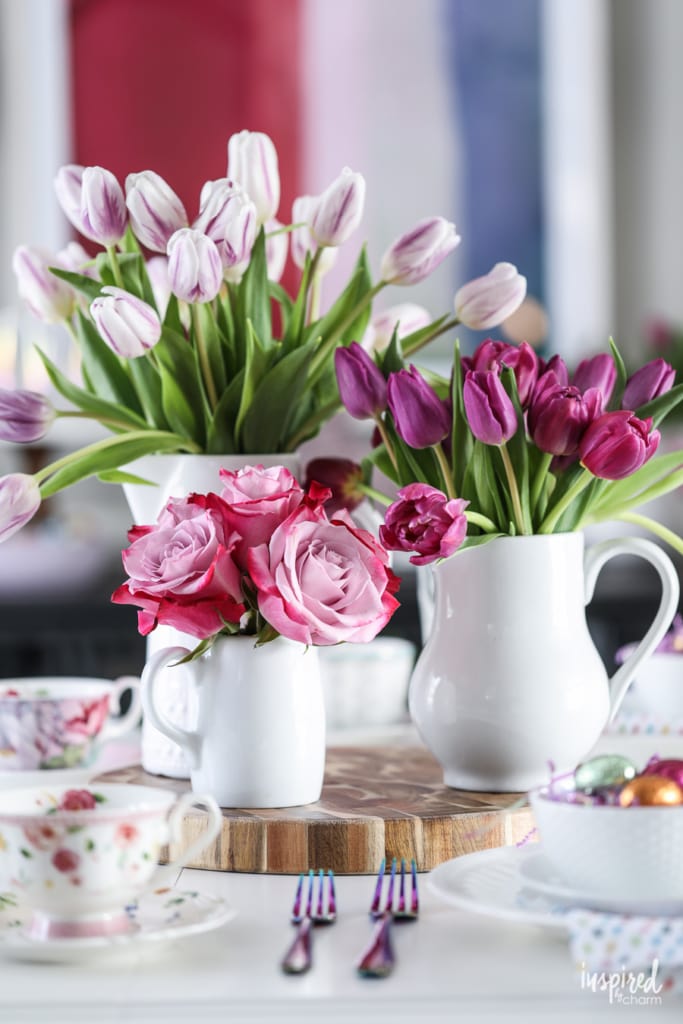tulips and roses in vases on a dining table.