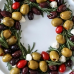 plate with a wreath made from olives, herbs, and cheese.