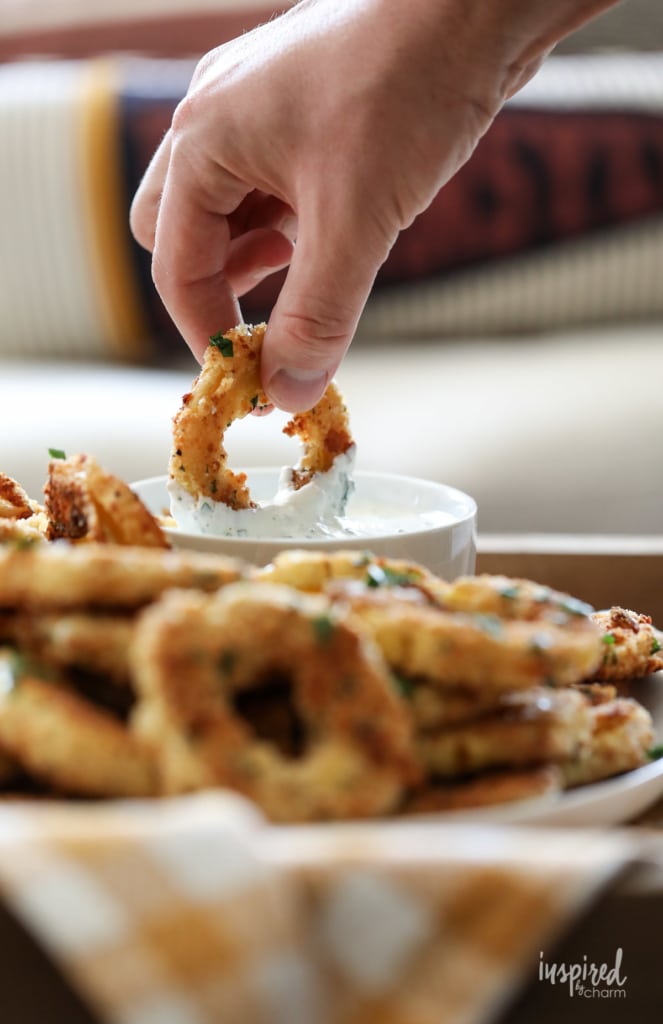 hand dipping Baked Delicata Rings into Creamy Herb Dip.