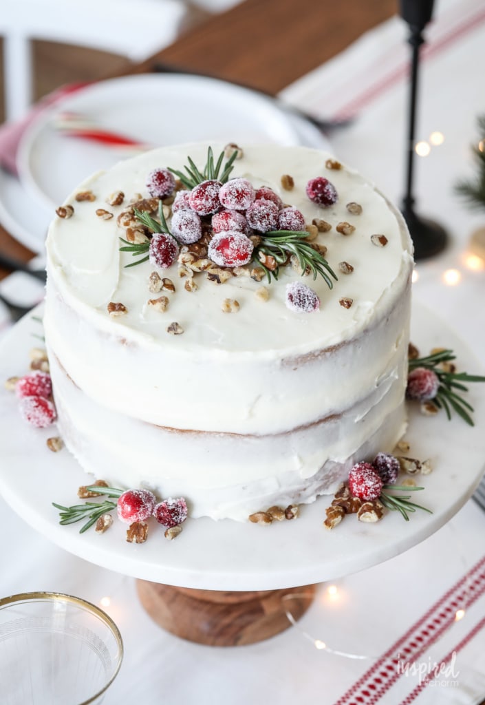 white iced cake topped with walnuts and candied berries