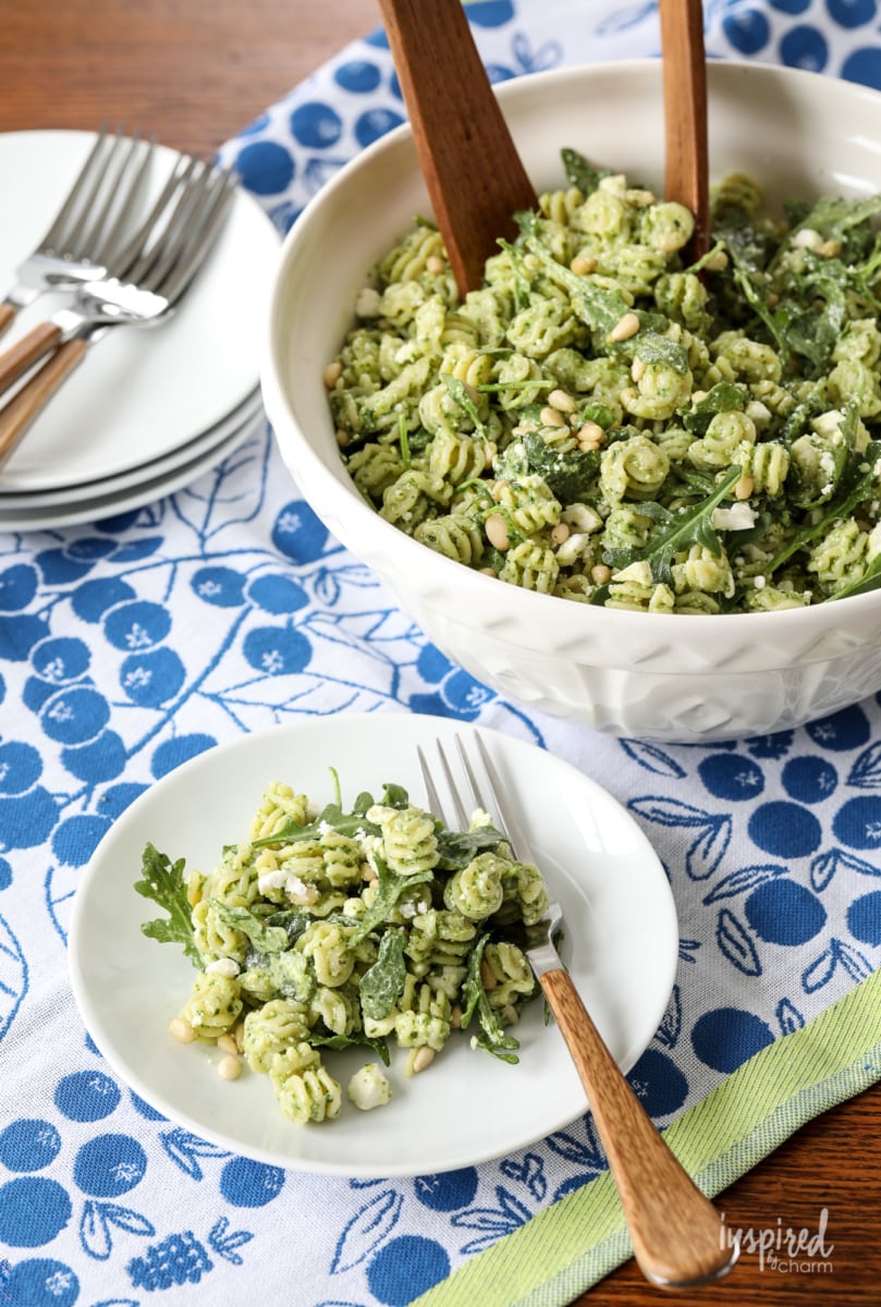 bowl of  Pine Nut and Arugula Pesto Pasta Salad with a serving on a plate.