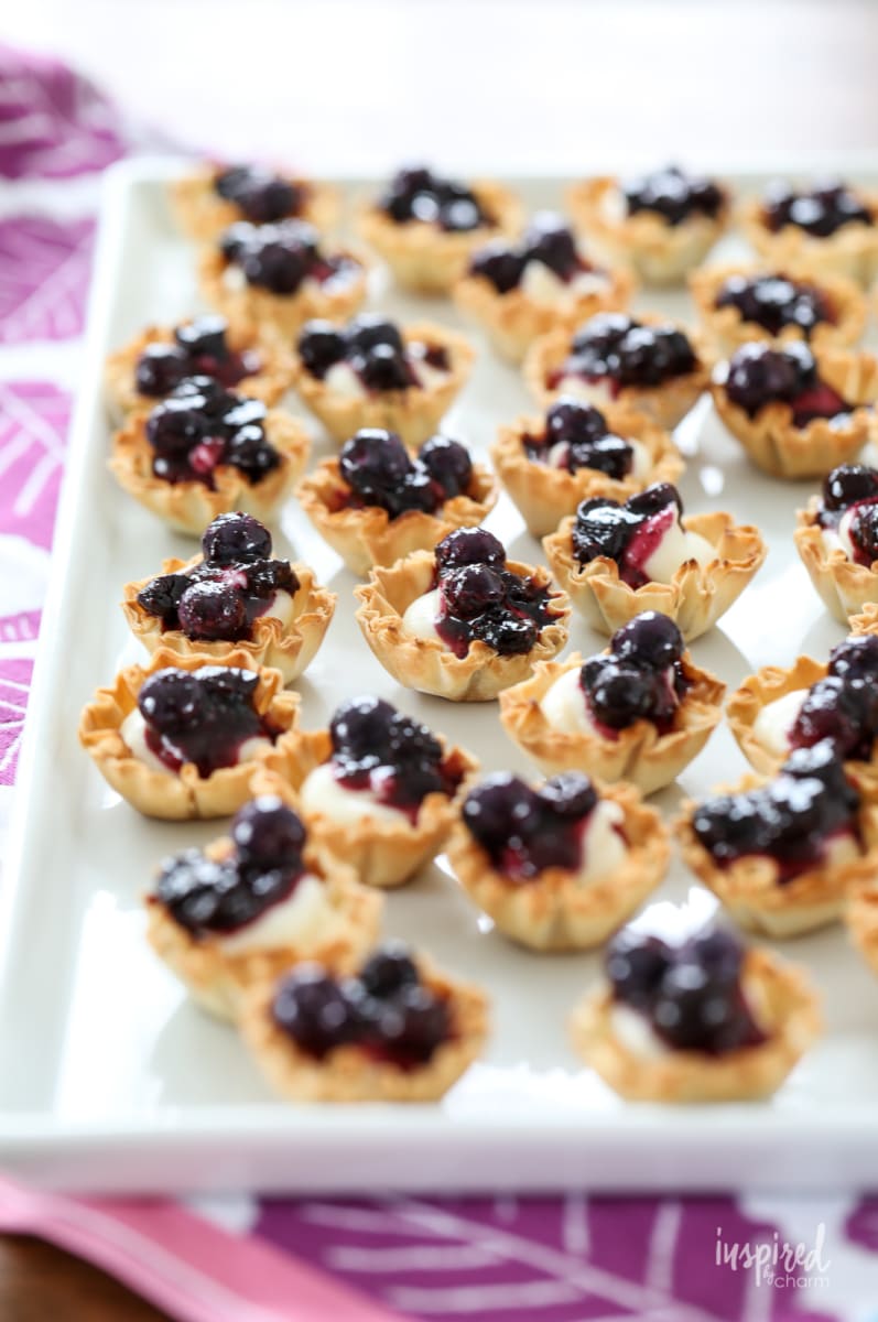 mini blueberry cheesecakes bites on a platter.