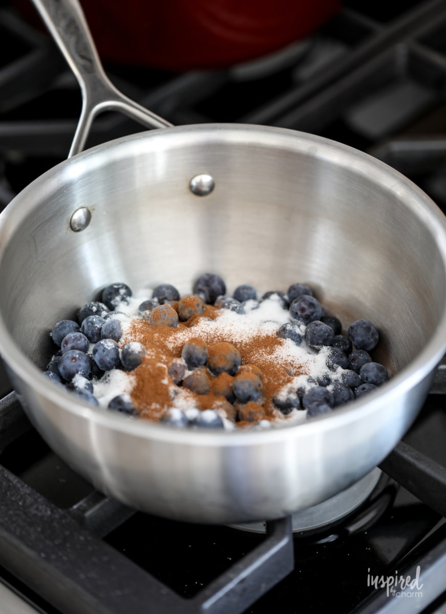 cooking blueberries in a sauce pan with sugar and cinnamon.