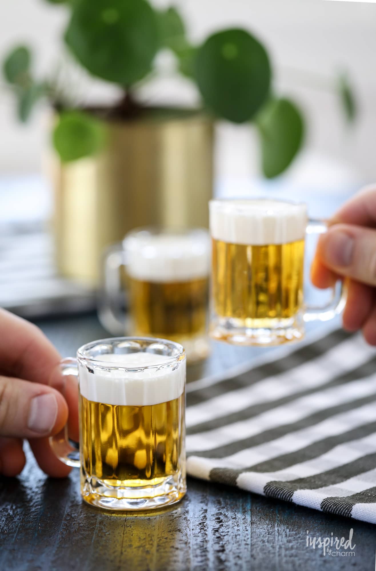 two hands holding two mini beer shots. 